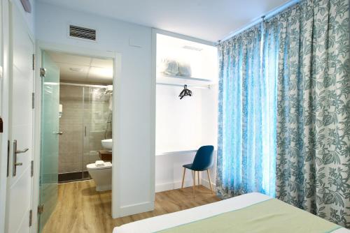 a bedroom with a blue shower curtain and a toilet at New Hostal Cabañas in Carboneras de Guadazaón