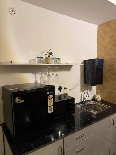 a kitchen with a microwave and a sink at Fifth Heaven Studio at Spectrum Mall in Noida