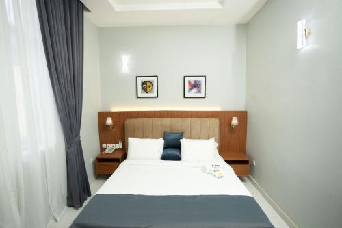 a bedroom with a large white bed with blue pillows at Habor Hotel & Suites- Abuja in Abuja