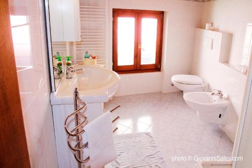 a white bathroom with a sink and a toilet at Appartamenti Il Castellaccio in San Siro