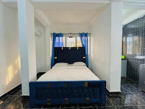 a bedroom with a blue bed and a shower at CAMERHOME Lycée Cité des palmiers in Douala