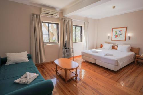 ein Hotelzimmer mit einem Bett und einer Couch in der Unterkunft Portimão Center Hotel by Umbral in Portimão
