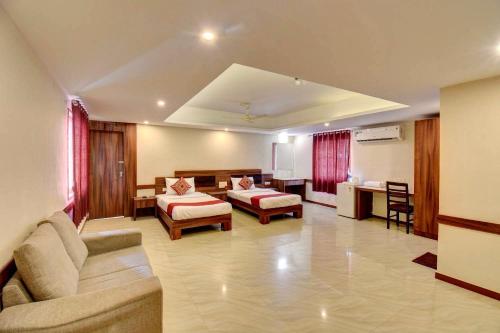 a living room with a couch and a bed and a desk at Sai Arya Residency By The Avyaan in Mangalore