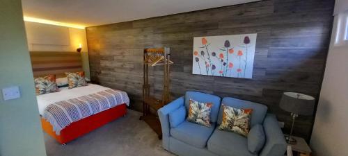 a bedroom with a bed and two blue chairs at Thistles Studio - Near Newark & Stubton Hall in Claypole
