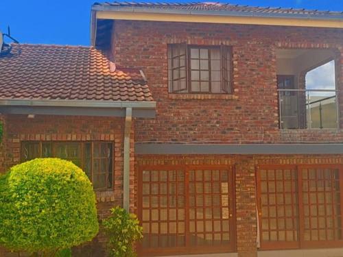 a red brick house with two garage doors at Milasha Guest House in Louis Trichardt