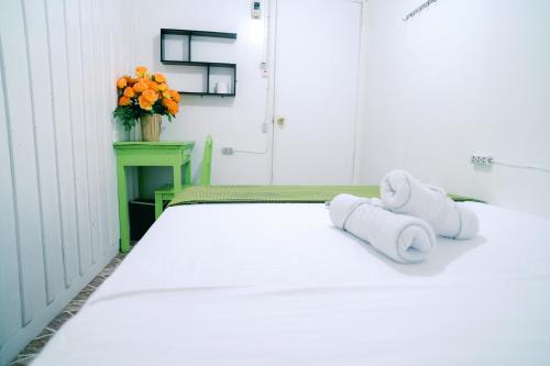 a white bed with towels on it with a vase of oranges at Green Lodging House in Anda