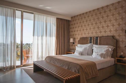 a hotel room with a bed and a large window at Wine & Books by the Sea, Algarve Resort in Albufeira