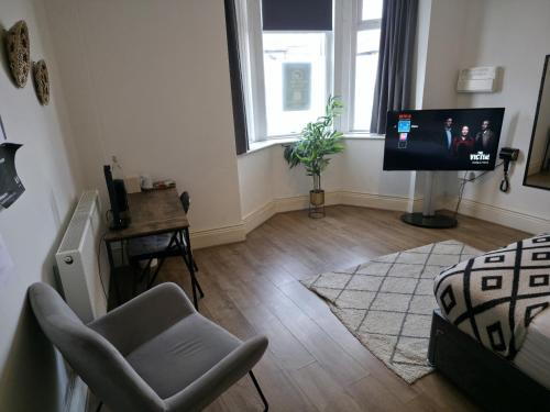 a living room with a chair and a television at West Beck House Newcastle - Spacious Double Room in North Shields