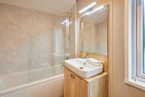 a bathroom with a sink and a bath tub at Sandy Lane 18 - Lodge with Hot Tub in Allerthorpe
