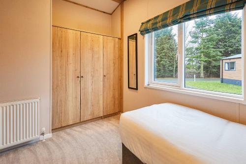 a bedroom with a bed and a large window at Sandy Lane 18 - Lodge with Hot Tub in Allerthorpe