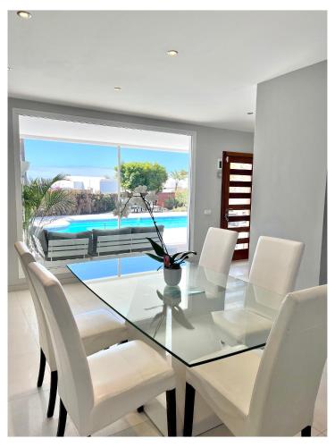 a dining room with a glass table and white chairs at Villa Infinity Exclusive in Tías