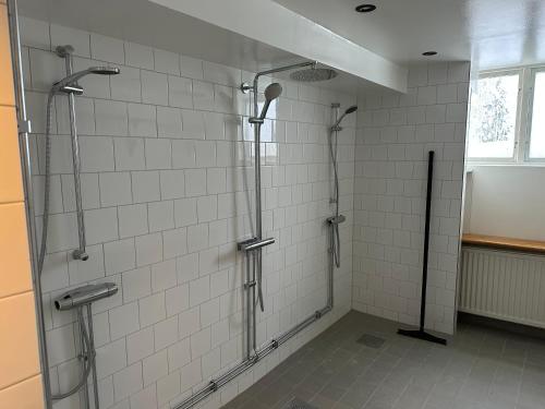 a shower in a bathroom with white tiles at Lillskarvens vandrarhem in Funäsdalen