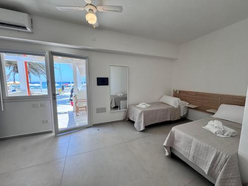 a bedroom with two beds and a balcony with the ocean at Lido Di Alghero Beach Resort in Alghero
