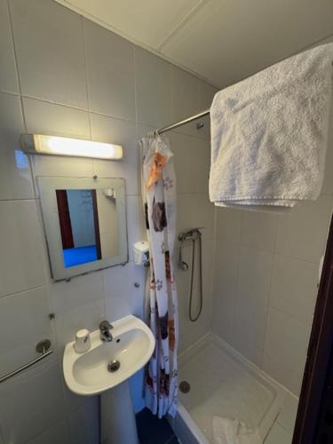 ein weißes Badezimmer mit Waschbecken und Dusche in der Unterkunft Hotel Chevallier in Levallois-Perret