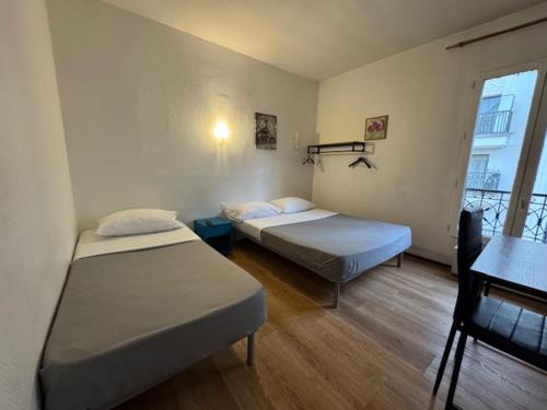 ein Schlafzimmer mit zwei Betten, einem Schreibtisch und einem Fenster in der Unterkunft Hotel Chevallier in Levallois-Perret