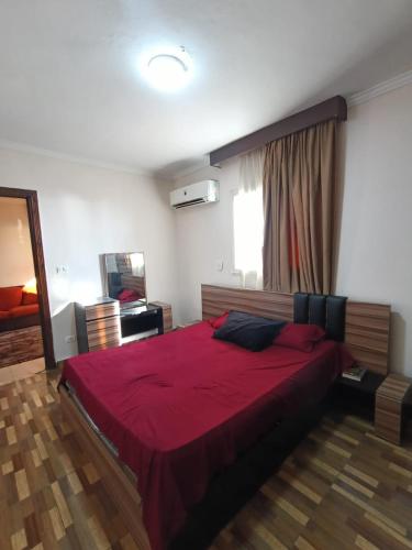 a bedroom with a large bed with a red blanket at Ibiza beach apartments in Alexandria