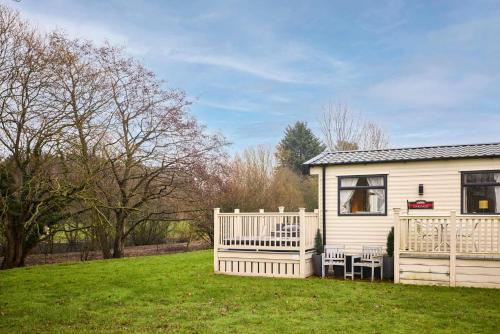 a small white house with a white fence in a yard at The Major Oak Lodge with Hot Tub in York