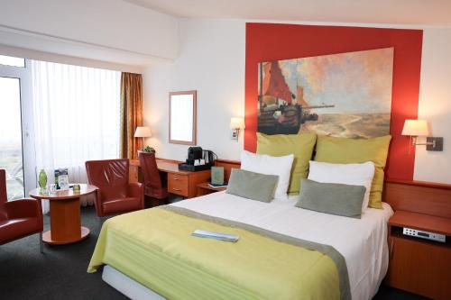 a hotel room with a large bed and a desk at Hotel Noordzee in Katwijk aan Zee