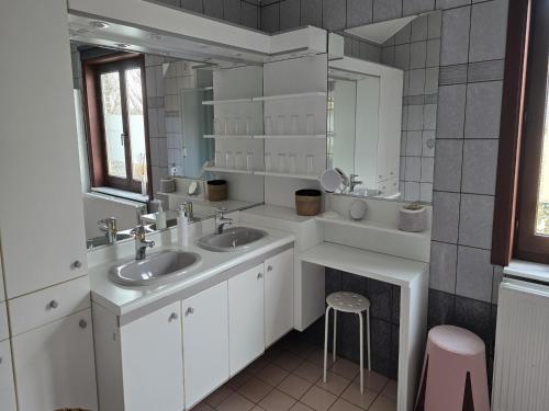 a bathroom with two sinks and a mirror and a stool at Group accommodation in Borgloon Hof Van Kalenberg in Borgloon