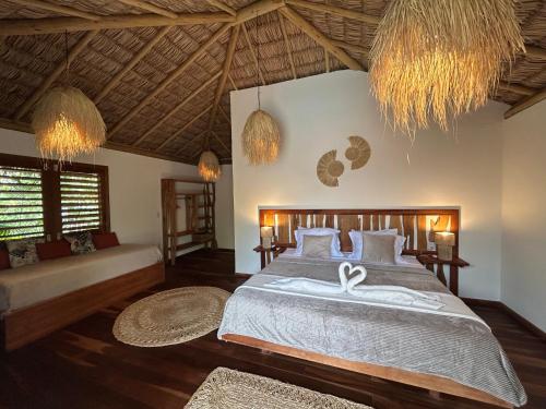 a bedroom with a bed and a couch and chandeliers at Tiki Pool's Bungalows in Fortim