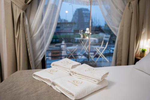 two towels sitting on top of a bed with a window at Villa Garden Boutique Hotel Tirana in Tirana
