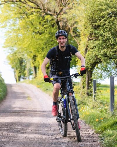a man riding a bike down a dirt road at Camping Les Pommiers in Comblain-au-Pont