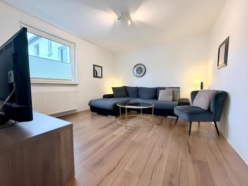 a living room with a blue couch and a tv at FeWo Lindenallee Modern & Ruhig in Nordhorn