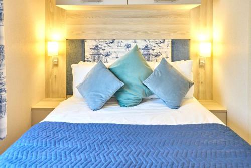 a bed with blue pillows on top of it at Cedar Lodge With Hot Tub in Pocklington