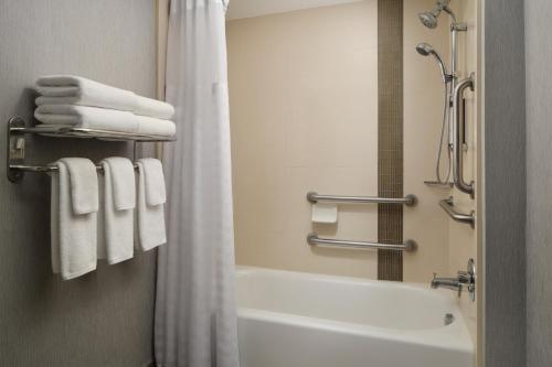 a bathroom with a tub and a shower with towels at Hyatt Place Tampa Airport/Westshore in Tampa