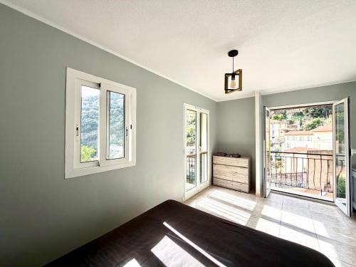 a bedroom with a bed and two windows at Maison Azurélienne in Menton