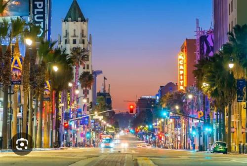 a city street at night with traffic lights and palm trees at 2Bed Apt View of Hollywood Sign & Rooftop Pool in Los Angeles