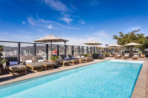a swimming pool with chairs and umbrellas on a building at 2Bed Apt View of Hollywood Sign & Rooftop Pool in Los Angeles