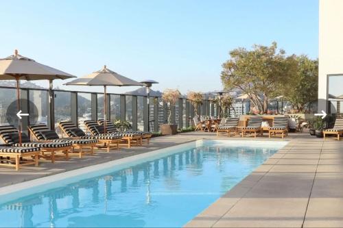 a swimming pool with chairs and umbrellas on a building at 2Bed Apt View of Hollywood Sign & Rooftop Pool in Los Angeles