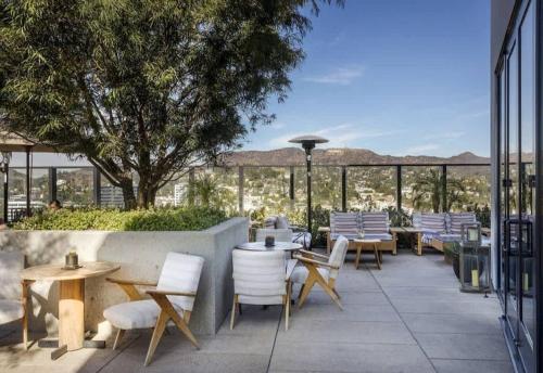 a patio with tables and chairs and a view of the mountains at 2Bed Apt View of Hollywood Sign & Rooftop Pool in Los Angeles