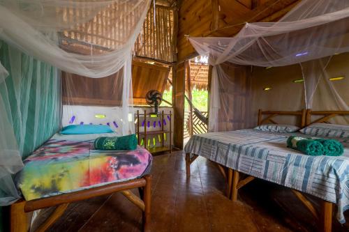 a bedroom with two beds with mosquito nets in it at Raízes Eco Hostel in Barra Grande
