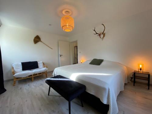 a bedroom with a large white bed and a chair at Bandrew in Stoumont