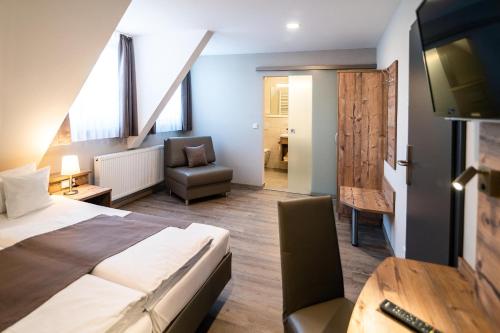 a hotel room with a bed and a chair and a television at Hotel-Gasthof Neue Post in Leutershausen