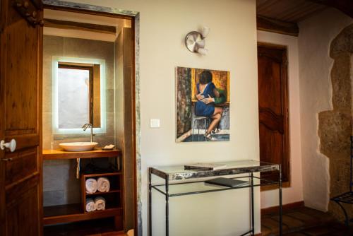 a bathroom with a sink and a painting on the wall at L'Oustalou in Rosières