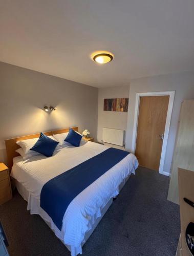 a bedroom with a large white bed with blue pillows at The Jolly Brewers in Bishops Stortford