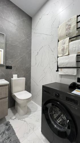a bathroom with a washing machine and a toilet at Квартира подобово класу "ЛЮКС" in Khmelnytskyi