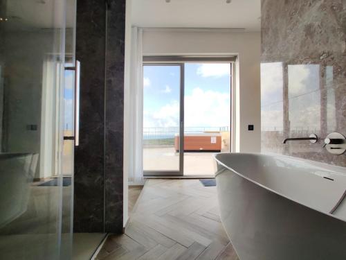 a bathroom with a tub and a view of the ocean at Villa Lippia in Misraħ Miel