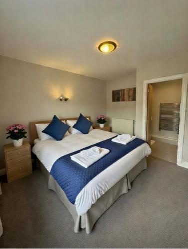 a bedroom with a large bed with blue pillows at The Jolly Brewers in Bishops Stortford
