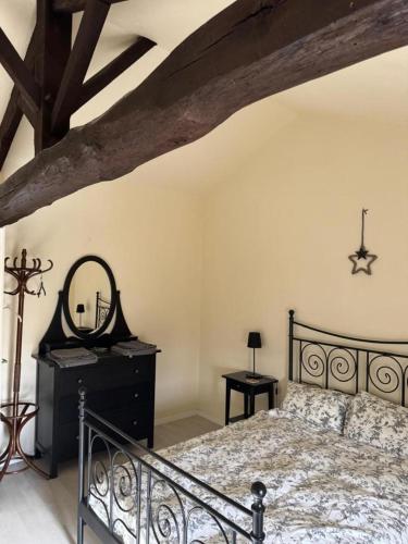 a bedroom with a bed with a mirror and a dresser at Les volets bleus in Saint-Saviol