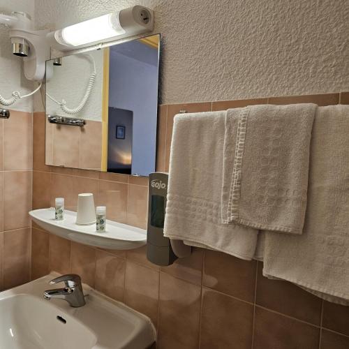 a bathroom with a sink and a mirror and towels at Hotel du Commerce et de Navarre in Lourdes