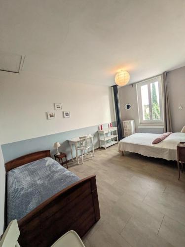 a bedroom with two beds and a table and chairs at Quiet house, sun and pool in Le Thor