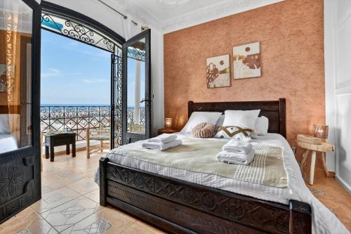 a bedroom with a bed with a view of the ocean at Adrar Lodge - Boutique Guesthouse with Sea View in Tamraght Ouzdar