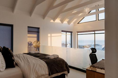a bedroom with a bed and a desk and windows at Beyond The Beach in Yzerfontein