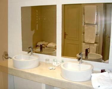 a bathroom with two sinks and a mirror at Hôtel des Pyrénées in Saint-Jean-Pied-de-Port