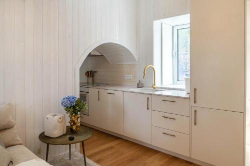 a kitchen with white cabinets and a sink and a table at Grão de Areia - Mosteiros - 50m da praia - piscina privada in Mosteiros