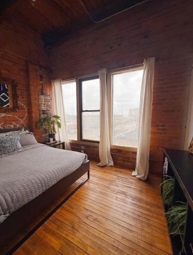a bedroom with a bed and two large windows at 420 Friendly SKYLINE view Downtown Loft FREE Parking in Detroit